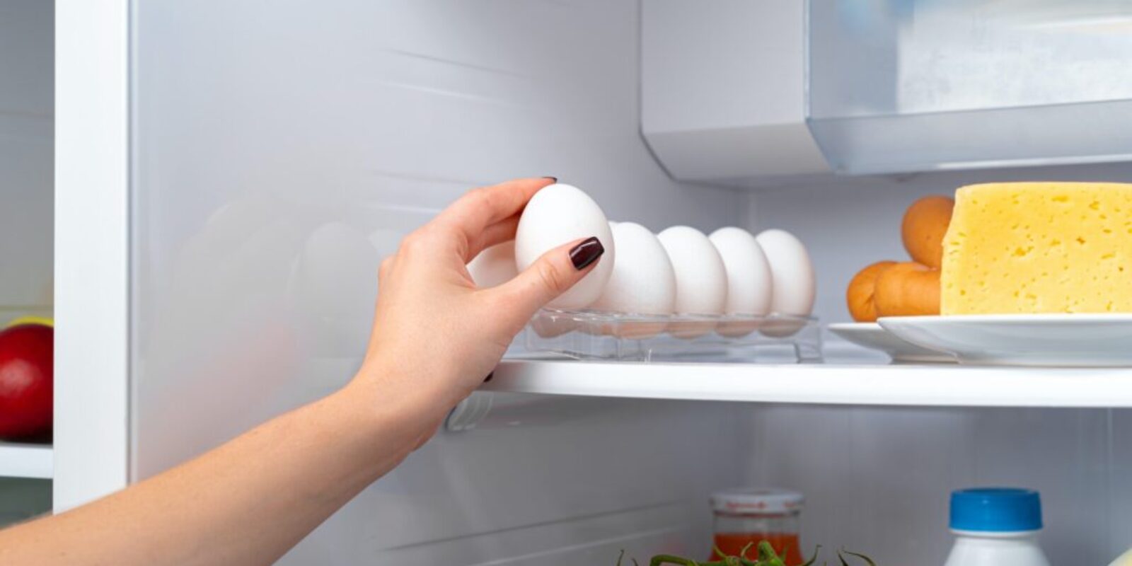 Female hand taking egg from a fridge